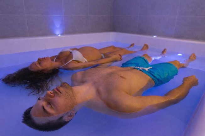 Paar schwebt entspannt nebeneinander im Floating-Becken